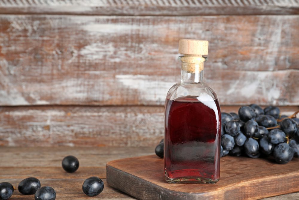 Bouteille en verre avec vinaigre de vin et raisins frais sur une table en bois